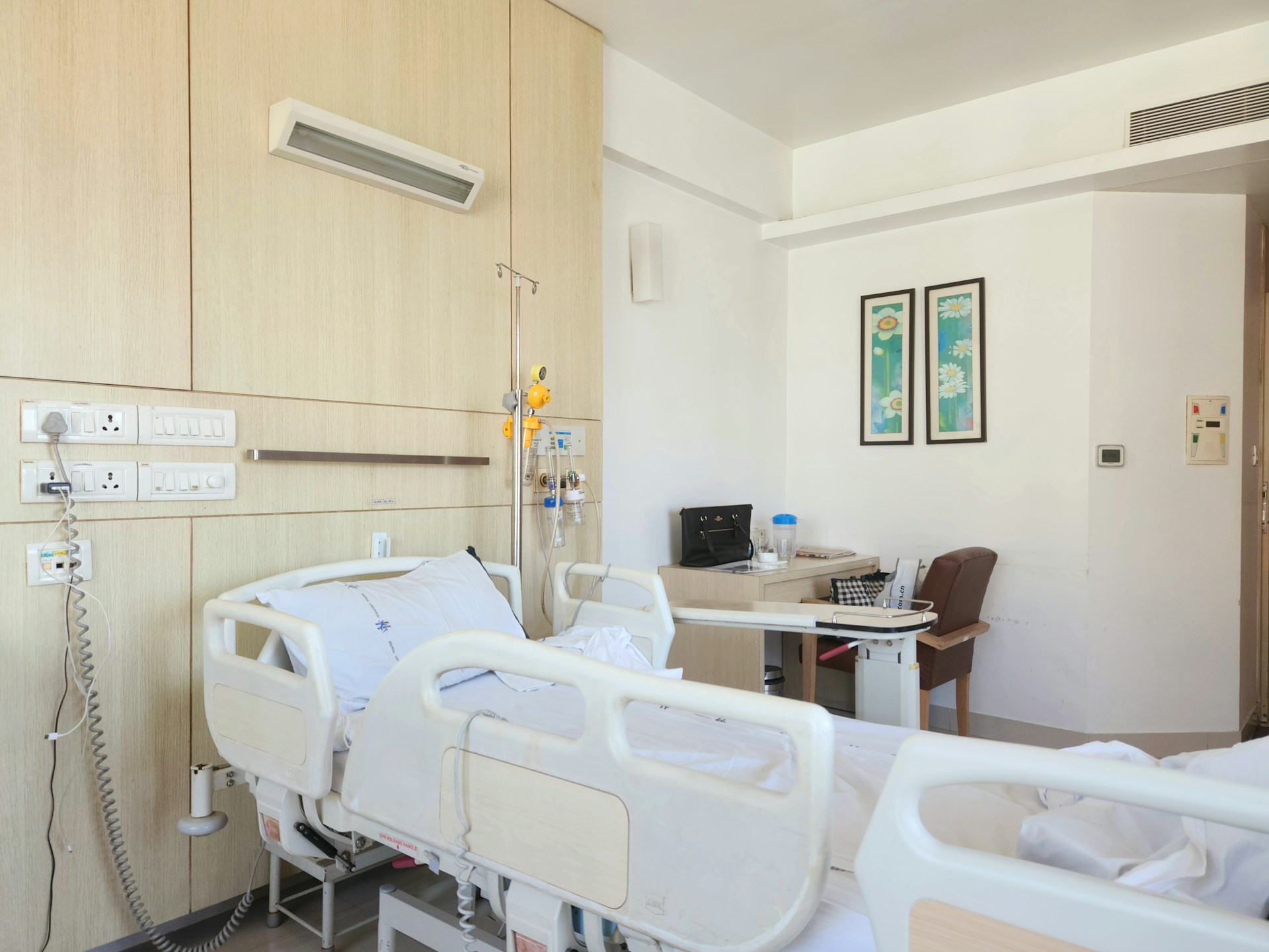 Bright private clinic patient room with hospital bed and bedside desk